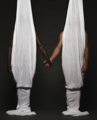 nude men holding hands, bodies obscured by hanging sheets