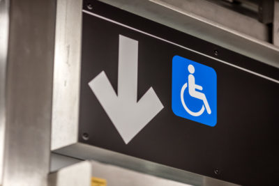 MTA elevator sign with arrow pointing down with wheelchair next to it