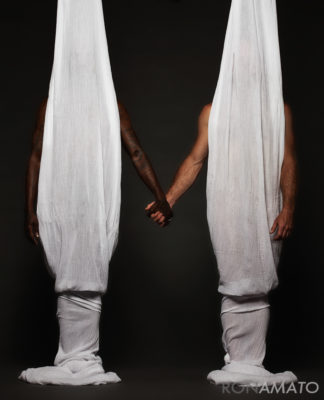 Two men hidden behind curtains holding hands