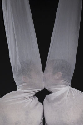 two men kissing through transparent white sheets