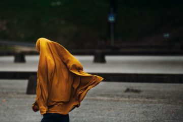 faceless woman wearing a hijab that is blowing in the wind