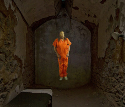 still from Michelle Handelman's Beware the Lily Law, with an inmate in an orange jumpsuit