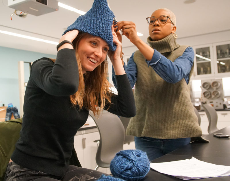 A student tries on a hat she knitted.
