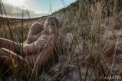 nude men kissing on the beach among grasses