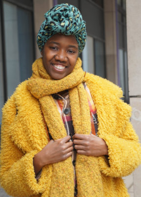 Young african american woman with teal leopard rpint head wrap and mustard yellow coat