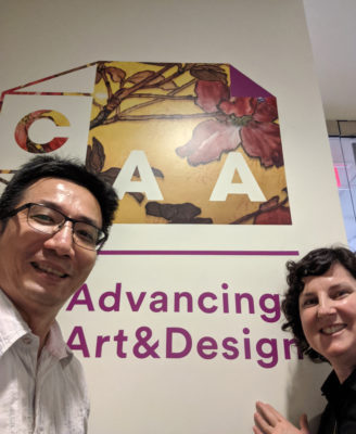 CJ Yeh and Austin Thomas post in front of CAA poster