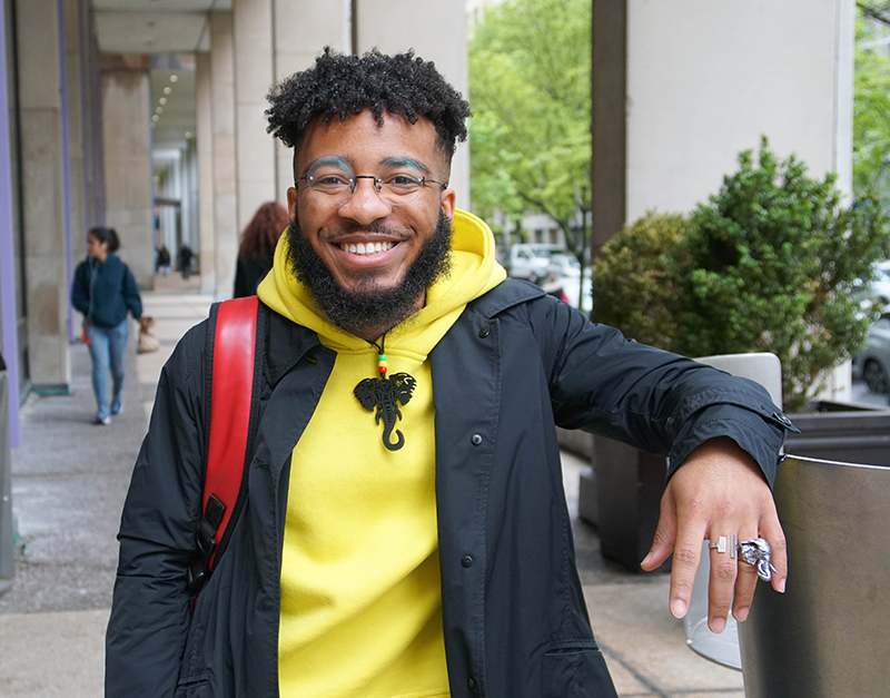 Young smiling african american man in with glasses and beard, Yellow hooded sweatshirt and black jacket.