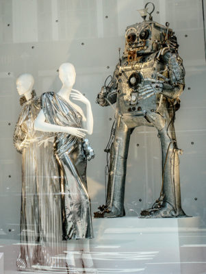 two mannequins in metallic dresses with metal robot sculptures