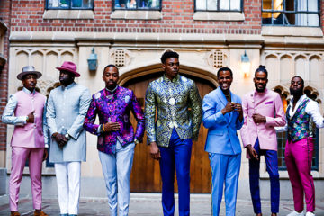 seven men stadning in a line in brightly colored suits