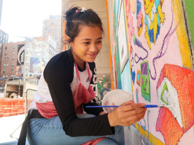Young woman painting on wall