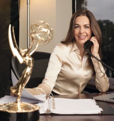 Elise Doganieri sitting at a desk behind her Emmy award trophy