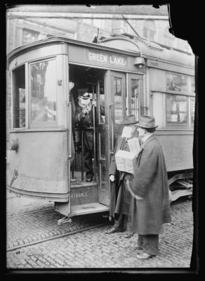 Men boarding a streetcar wearing masks.