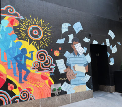 Mural of silhouetted singers and a man throwing papers on black background