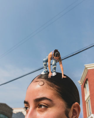top of woman's head with a small version of herself balancing on top