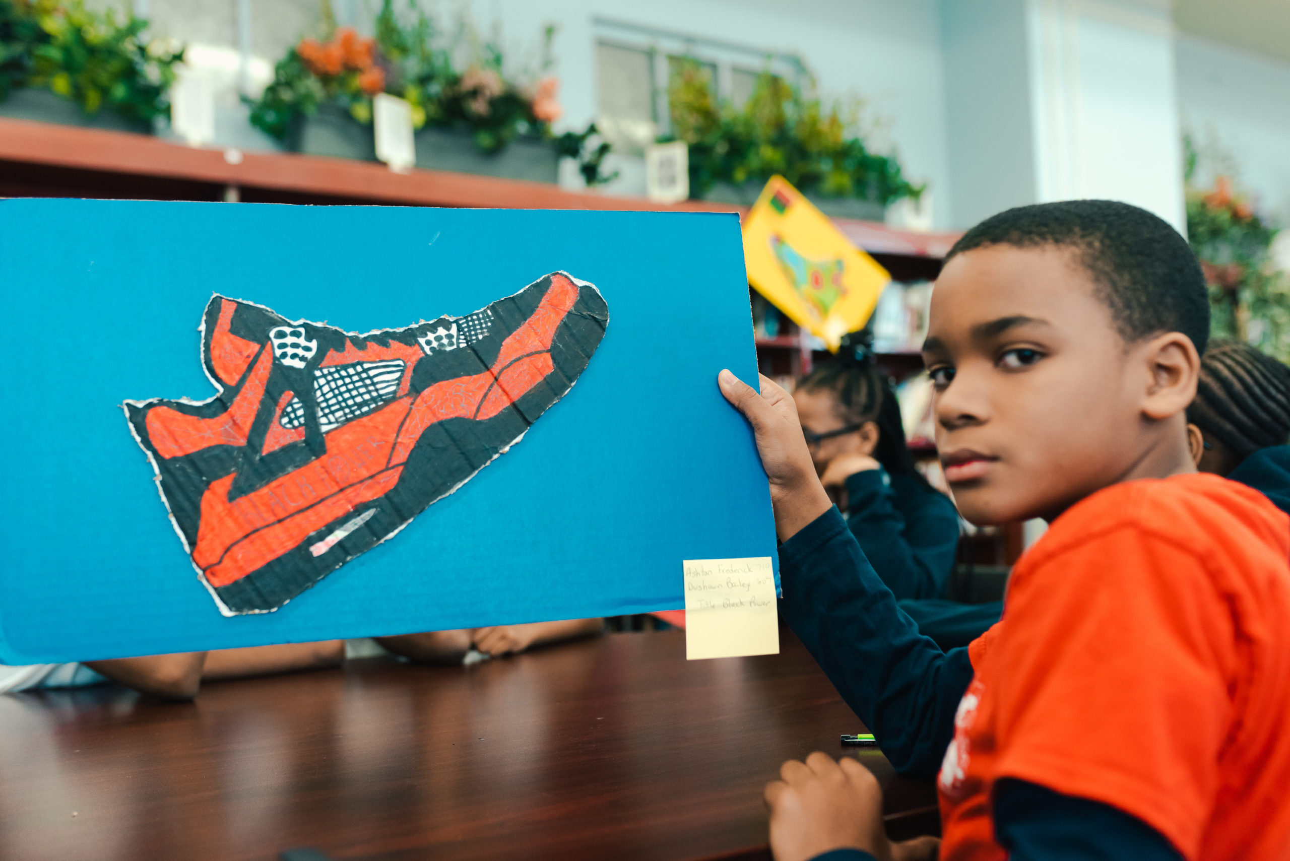 Boy holding drawing of orange sneaker