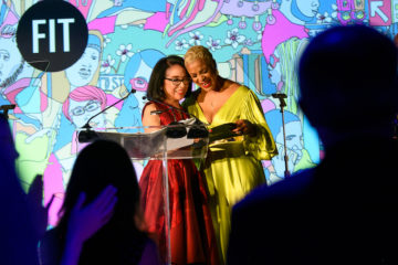 President Joyce F. Brown standing at a podium smiling next to FIT gala honoree and alumna Brandice Daniel.
