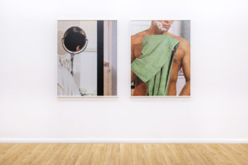 Two photographs hang on a white wall