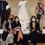 Three students sit in front of a white dress they designed at The Metropolitan Museum of Art.