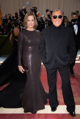 Sigourney Weaver in a shiny black floor length dress and Michael Kors in sunglasses and a black tuxedo