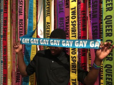 person standing amid colorful ribbons with gay pride messages