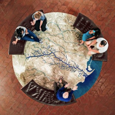 overhead view of people sitting around a round rug designed to look like a topological map