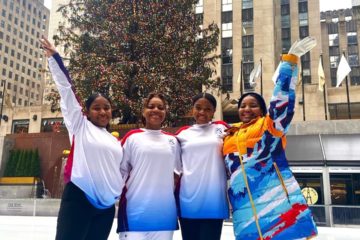 Figure skaters at Rockefeller Center standing with arms in the air