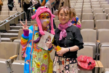 Yuniya Kawamura and a fan holding her book inside an auditorium.