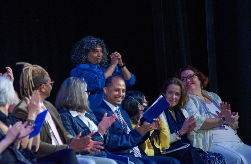 An audience of faculty dressed in blue regalia