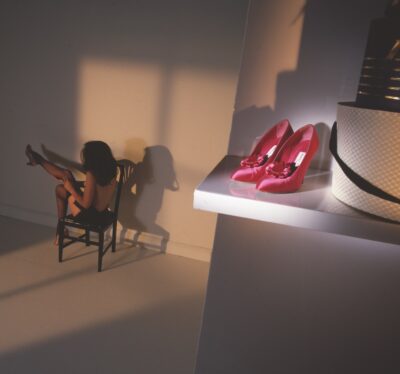 red Manolo Blahnik heels with woman sitting in the background