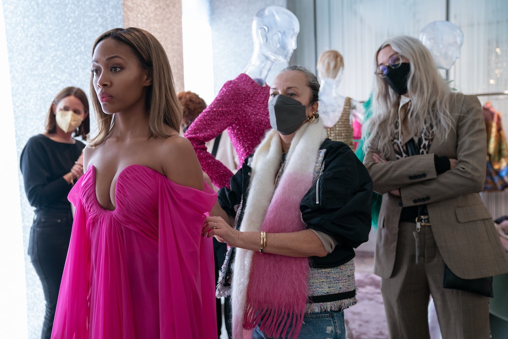 Nicole Beharie in a pink dress with costume designers behind her adjusting