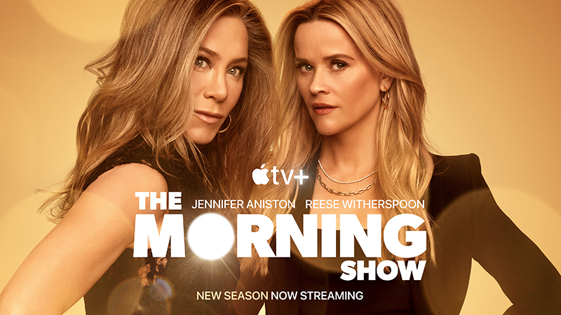Jennifer Aniston and Reese Witherspoon standing behind the logo for The Morning Show 