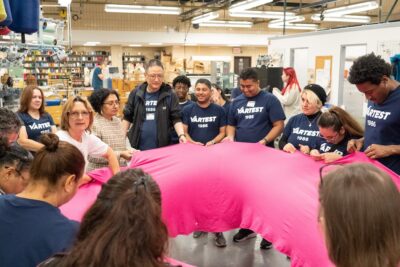 Students and faculty touching a large pink fabric