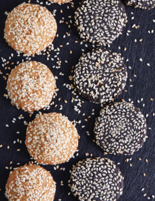 two rows of light brown and dark brown cookies with sesame seeds