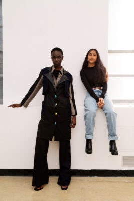 Kenisha Seth, Fashion Design BFA '24, sits on a wall while a model wears her garment