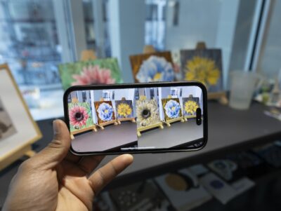 A phone showing three paintings of flowers through normal and colorblind vision