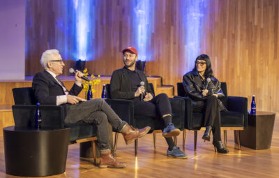 three people sitting on a stage in chairs talking