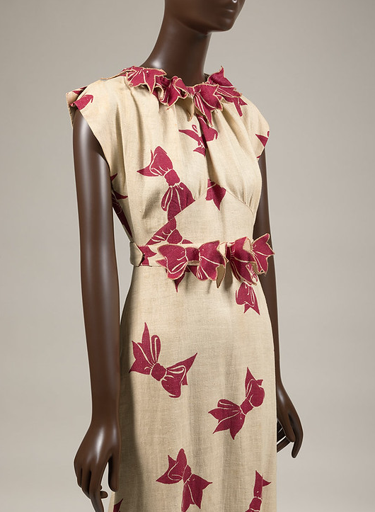 Beige dress with red bows imprinted on dress on a mannequin