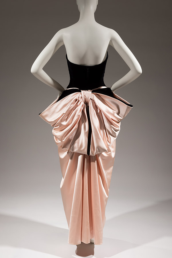 back of mannequin wearing black velvet and pink satin strapless dress with big pink bow on the back side
