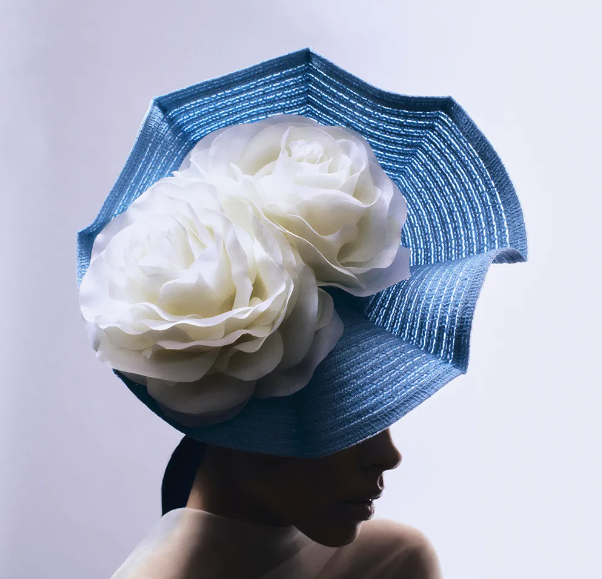 large blue hat with large white silk flowers in the center