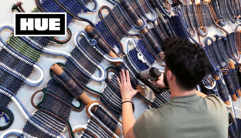 fiber artist William Storms installing large woven work on a wall; Hue logo