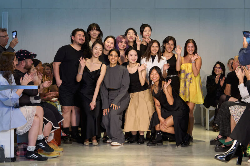 group of all Fashion Design MFA graduates at the and of their runway show accepting applause from the audience