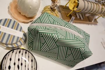 assorted gift options from the Style Shop on a table: a small bowl, coasters, a makeup bag, jewelry