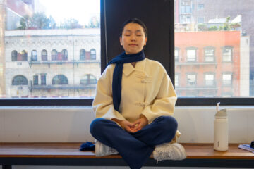 student sitting crosslegged on a bench with eyes closed