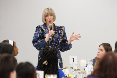 Kristy Fall talking into a microphone at the Baker Scholar dinner.