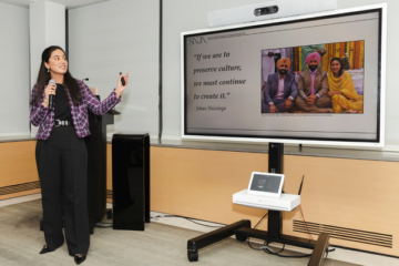 Harnoor Sekhon gives a presentation in front of a digital screen