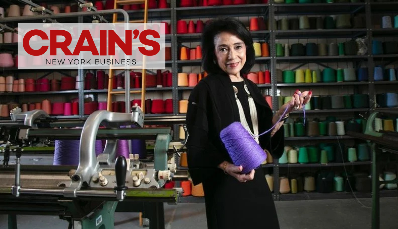 President Joyce F. Brown stands holding a large purple spool of thread in FIT's knitting lab; Crain's New York Business logo