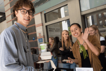 students on the FIT Breezeway smiling and waving with cups of herbs
