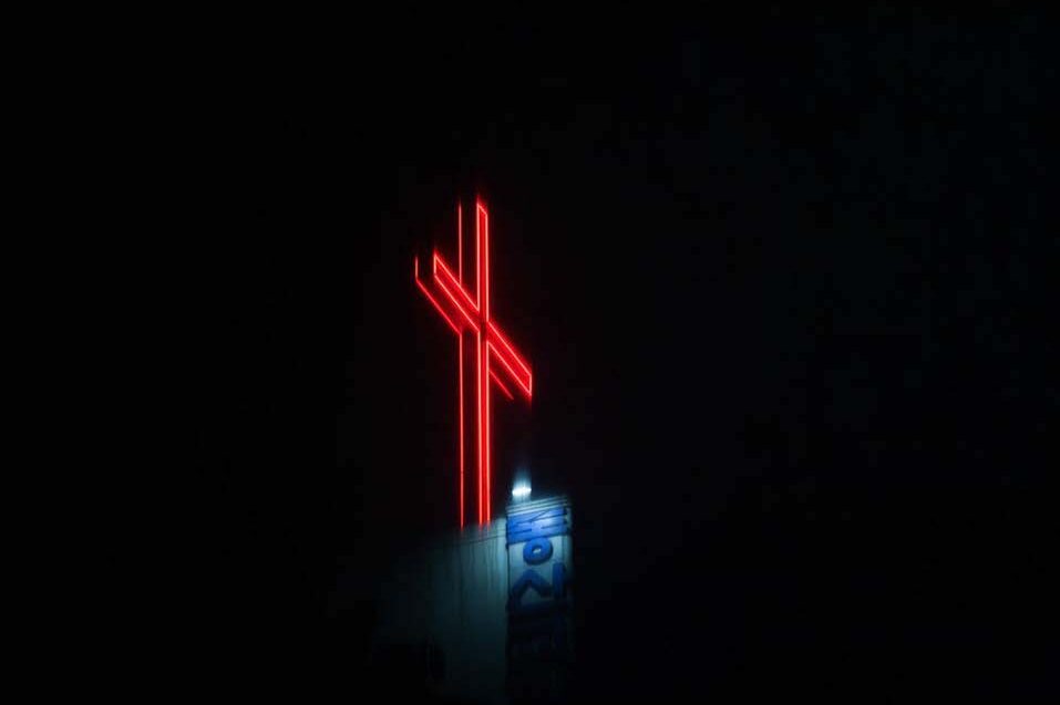 red neon cross against a black sky