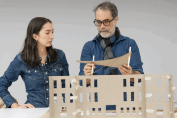 a student and teacher stand in front of a miniature exhibition model