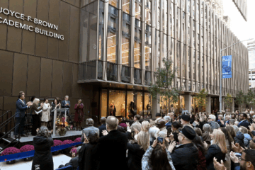 people stand outside FIT's new academic building for the ribbon cutting ceremony and naming of it as the Joyce F. Brown Academic Building